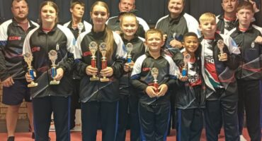 A photo of the Newcastle athletes holding trophies and their coaches who particptaed at the recent WAKO Kickboxing Championships