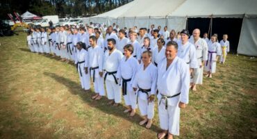 A photo taken of a large group of people dressed in karate attire standing outside a big white tent.