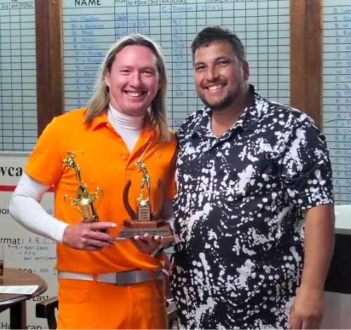 Two golfers are photographed in a club house holding a trophy.