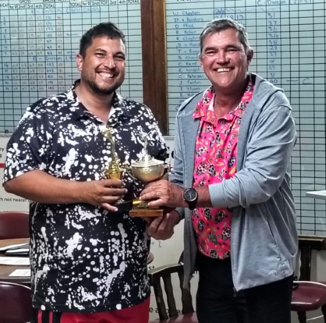 Two golfers are photographed in a club house holding a trophy.