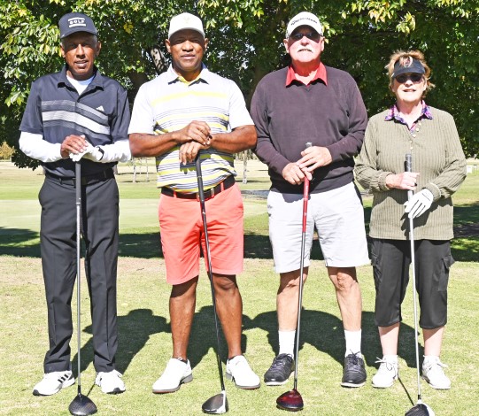Four golfers photographed in their golfing attire on a golf coarse.