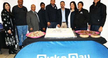 A group of people are photographed standing behind a blue pick n pay banner.