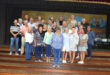 Group of former Dundee High students standing in a group on the stage in the school hall.