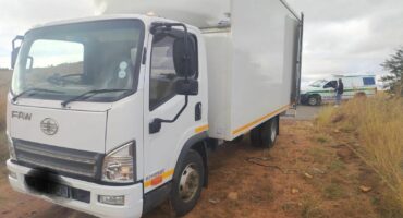 Image of a truck at the side of the road with a police van in the background.