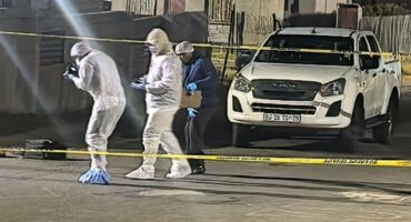 Image of men in protective gear adjacent to crime scene tape.