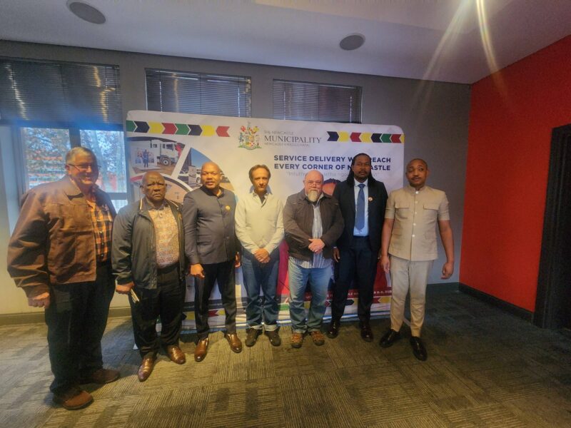 A photo iof a group of people, seemingly delegates at the Newcastle Municipality, standing in front of a municipal project banner.