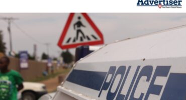 A large photo of a police van. People are spotted in the background by a padestrian crossing.