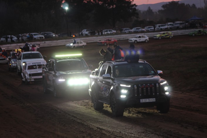 A photograph of several vehicles participaing in a lap around the racecoarse.
