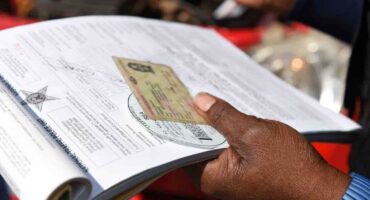 Image of a hand holding an application form and a driver's license.