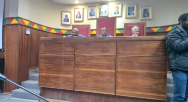 Image of three men in council chambers.