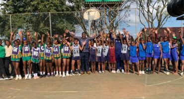 Image of young athletes in a group with their hands in the air.