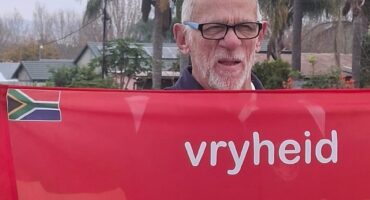 Image of an elderly man holding a Vryheid parkrun banner.