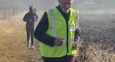 Image of a runner with a reflective jacket on a parkrun course.