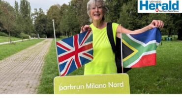 Image of woman holding a British and South African flag at parkrun Milano Nord.