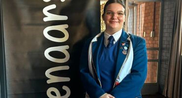 Image of a female learner from Hoërskool Pionier standing next to a 'Redenaars' banner.