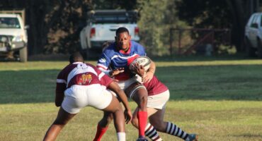 Image of a Sentraal rugby player being tackled by two Vryheid players.