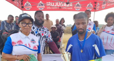An image of AbaQulusi Community Radio Station Manager, Busi Thusini handing out a trophy and sport kit to a player after the AbaQulusi FM Soccer Spectacular games held on Youth Day in Bhekuzulu.