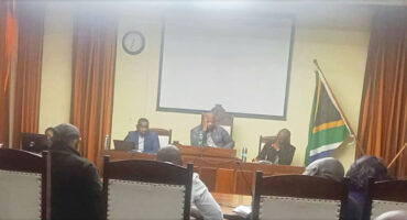 Image of councillors and officials around a horseshoe table in Endumeni Council Chamber.