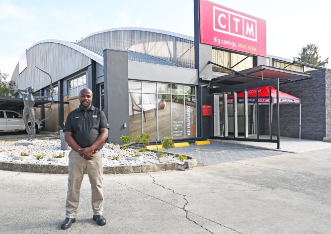 A proud store manager poses outsiude the Newcastle CTM store after its revamp.