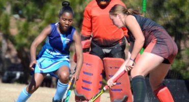 Image of girls' hockey players from Sarel Cilliers and Dundee High battling for the ball.