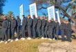 Photo of SAPS golf team members in tracksuits in front of a banner on a golf course.