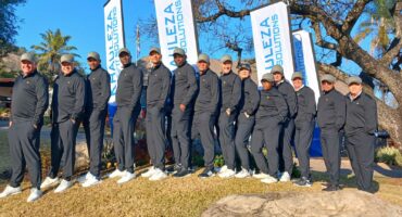 Photo of SAPS golf team members in tracksuits in front of a banner on a golf course.