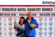 A photo of two bowlers holding trophys while standing in front of a red and white banner.