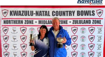 A photo of two bowlers holding trophys while standing in front of a red and white banner.