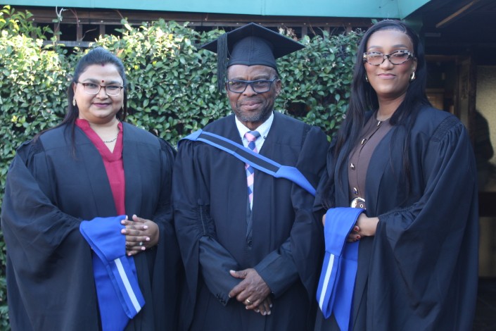 A group of graduates pose in front of a building.