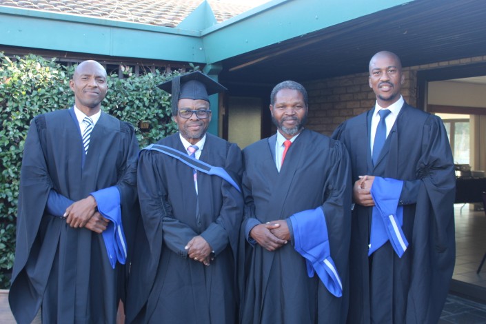 A group of graduates pose in front of a building.