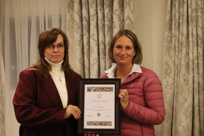 Two women are pictured holding a certificate during a formal function.