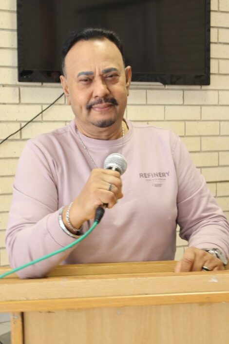 A man is photographed talking over a mic.