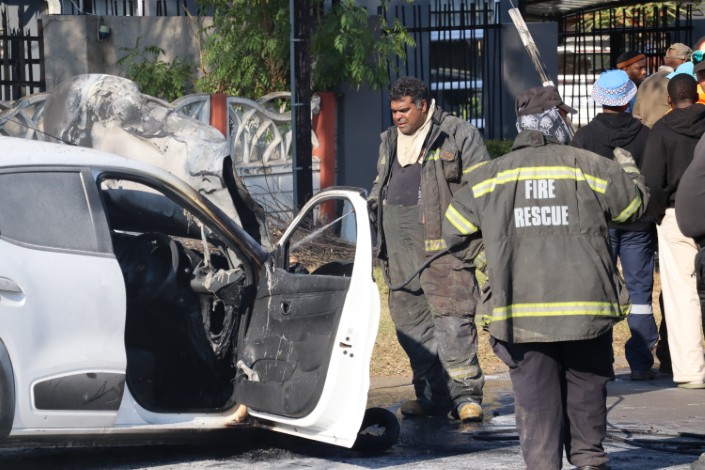 A photo of an accident scene, where firefighters are extinguishing flames after a vehicle set alight.