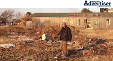 A photo taken of a man standing in an open field where illegal dumping is prevalent.