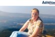 A photo of a woman sitting outside on a mountain.