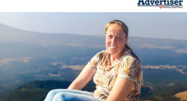 A photo of a woman sitting outside on a mountain.