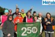 Image of group of parkrunners holding a 250 volunteer banner.