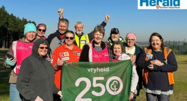 Image of group of parkrunners holding a 250 volunteer banner.