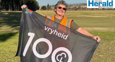 Image of a woman holding a 100th milestone parkrun flag.