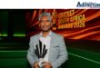 Newcast'es Rishi Nanan standing at a ceremony holding a trophy.