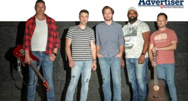 A group photo of a male orientated band posing in front of a black wall. Top corner is the Newcastle Advertiser logo.