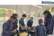 A photo taken of a group of children cooking in a school hall.