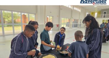 A photo taken of a group of children cooking in a school hall.