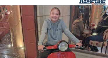 A photo of a young girl on ared scooter inside a restaurant.