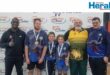 Image of four adult men and two children with medals in front of an Orange Grove Dairy banner.