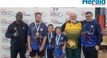 Image of four adult men and two children with medals in front of an Orange Grove Dairy banner.