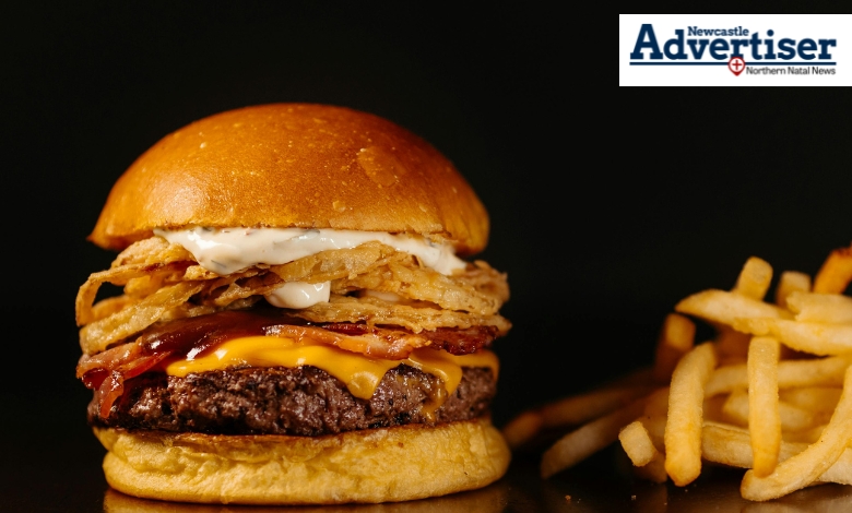 A burger and Chips in front of a black background.