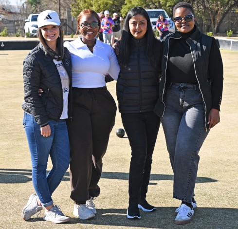 A group of women posing for a photo on a bowling field.