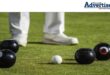 A generic image of bowls on strategically placed on the bowling greens with the legs and feet of a bowler seen in the background.