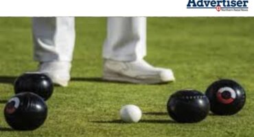 A generic image of bowls on strategically placed on the bowling greens with the legs and feet of a bowler seen in the background.